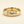 A gold band mens wedding ring with a hammered texture on the exterior and a polished interior by ring bear with comfort fit, set against a solid cream background.