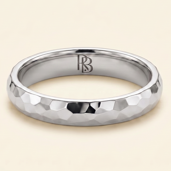 A Platinum band mens wedding ring with a hammered texture on the exterior and a polished interior by ring bear with comfort fit, set against a solid cream background.
