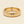 A yellow gold band mens wedding ring with a hammered texture on the exterior and a polished interior by ring bear with comfort fit, set against a solid cream background.