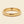 A yellow gold band mens wedding ring with a hammered texture on the exterior and a polished interior by ring bear with comfort fit, set against a solid cream background.