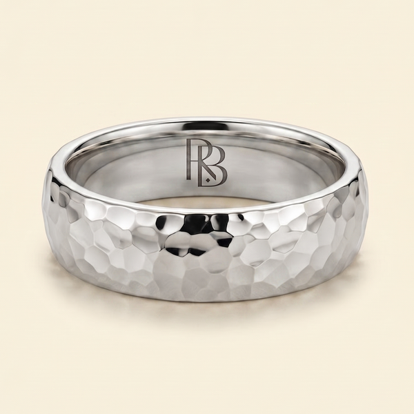 A platinum band mens wedding ring with a hammered texture on the exterior and a polished interior by ring bear with comfort fit, set against a solid cream background.